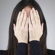 a woman in a black top hiding her face with hands