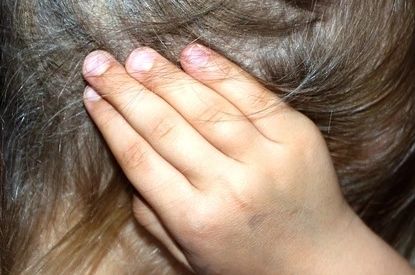a little girl having her hands on the ear