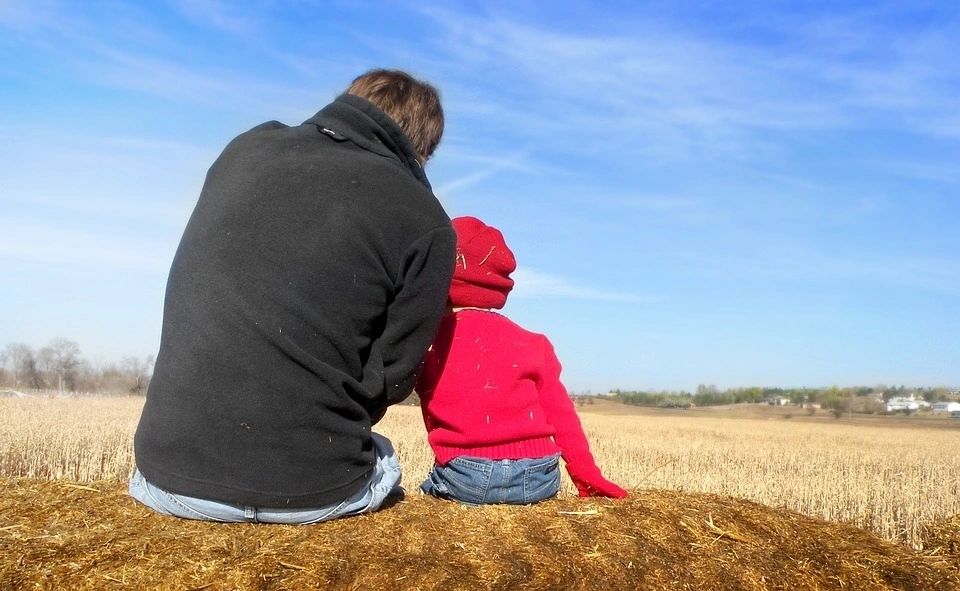 The Back of a Man and a Child on a Field