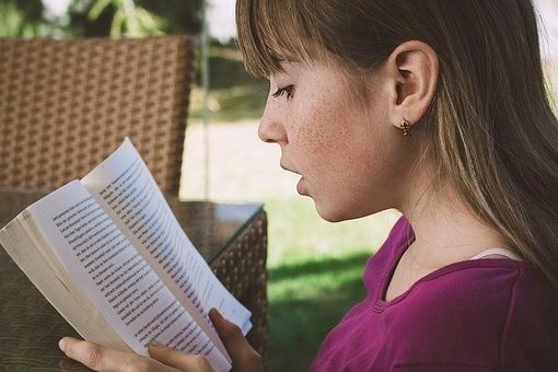 a girl in a purple top reading a book